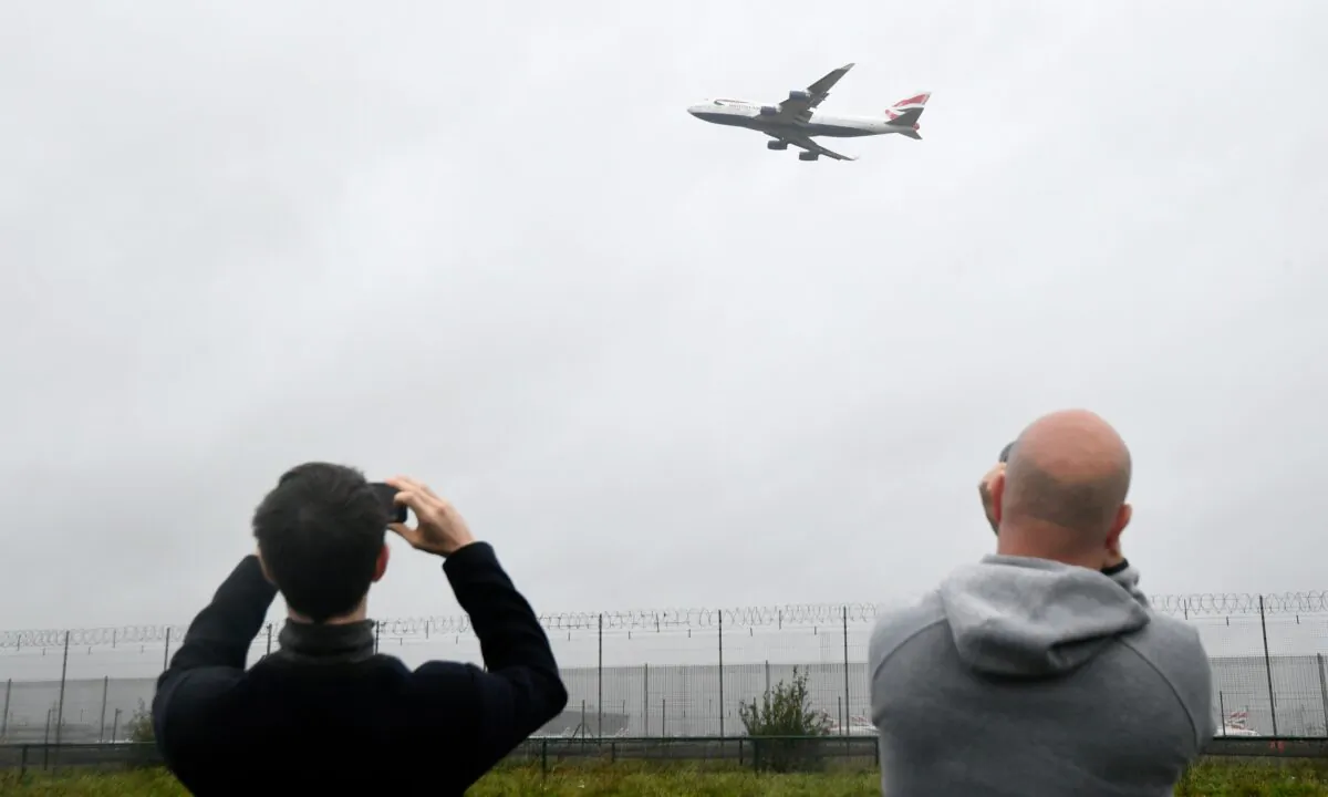 Spectators take images of a British Airways Boeing 747 as it does a flypast over London Heathrow airport on it's final flight, the last of 31 jumbo jets to be retired early by the airline due to the coronavirus disease (COVID-19) pandemic, in London, Britain, on Oct. 8, 2020. (Toby Melville/Reuters)
