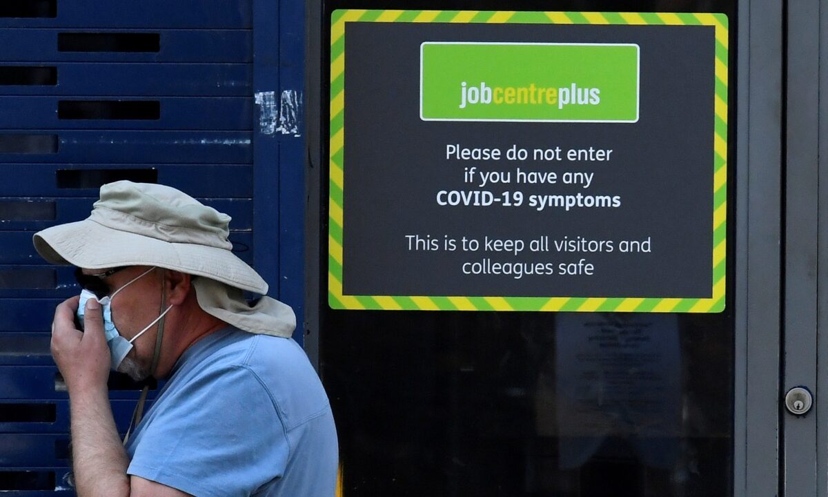 A person wearing a protective face mask walks past a Job Centre Plus office