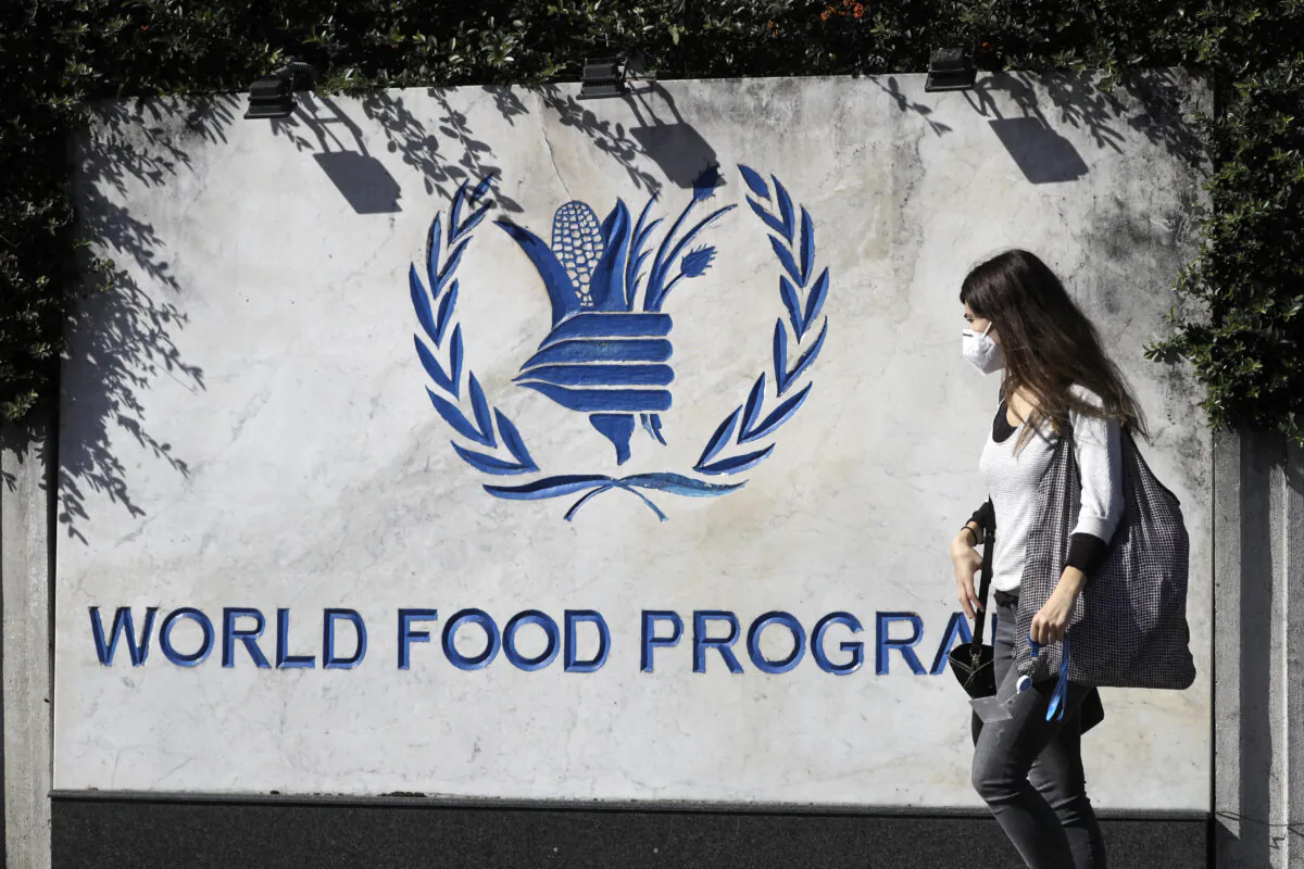 A woman walks past a sign at the entrance of the United Nations World Food Program (WFP), in Rome on Oct. 9, 2020. (AP Photo/Gregorio Borgia)