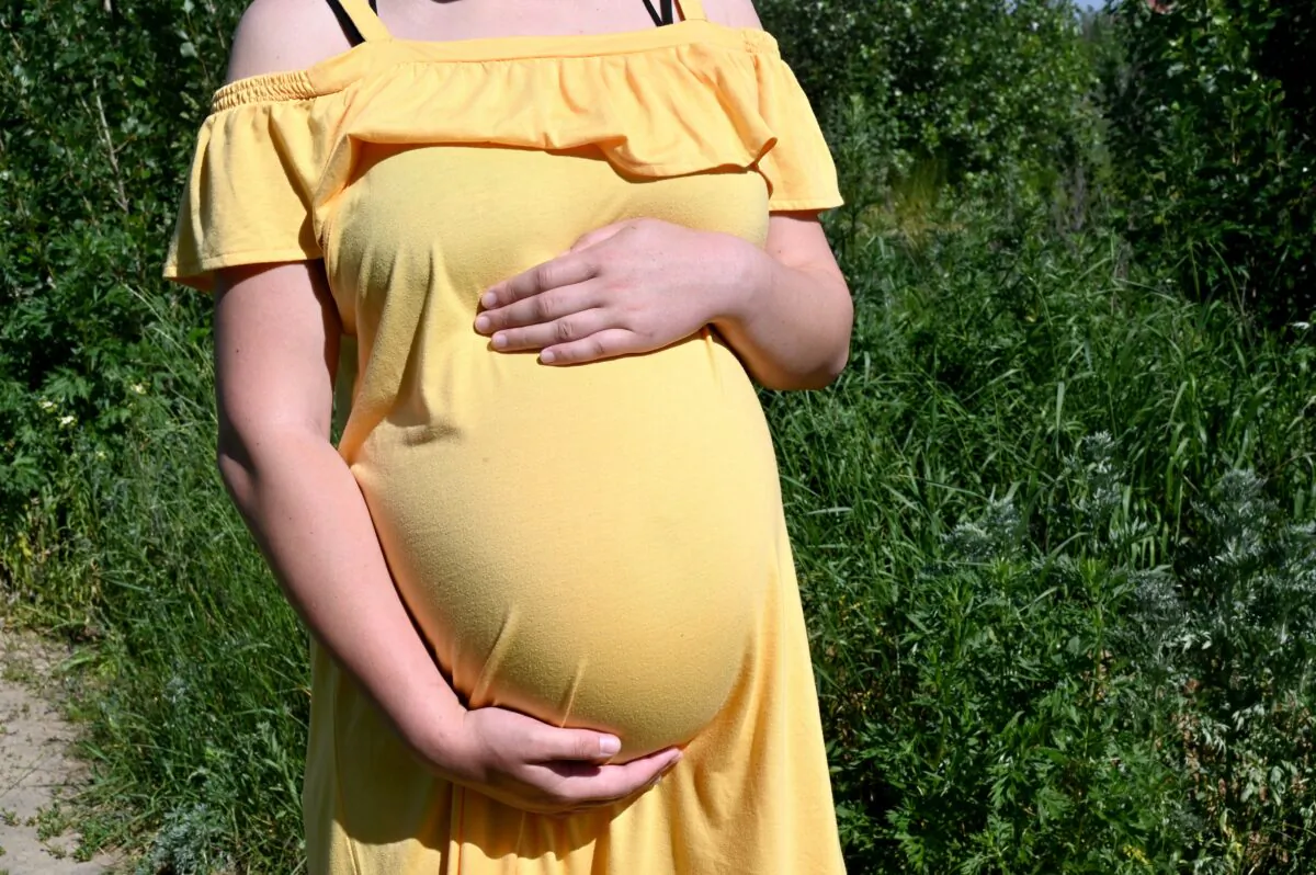 Olga, a 26-year-old serving as a surrogate and expecting twins for a Chinese couple, holds her belly as she walks in the town of Sophiya Borshchagivka, near Kyiv, Ukraine, on June 12, 2020. (Sergei Supinsky/AFP via Getty Images)