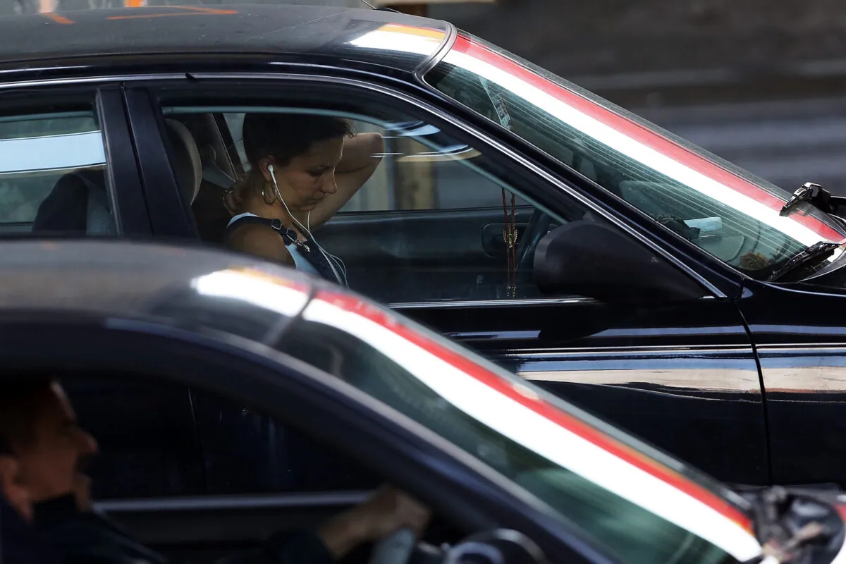 A driver uses a phone with earphones on while behind the wheel of a car in New York City in a file photo. (Spencer Platt/Getty Images)