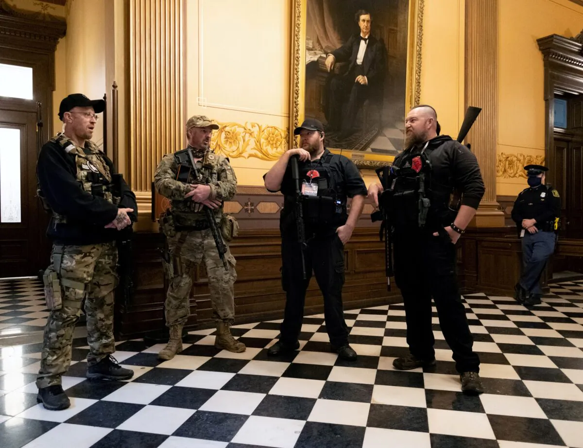 Members of a militia group, including Michael John Null and Willam Grant Null, right, who were charged on Oct. 8, 2020, for their involvement in a plot to kidnap the Michigan governor, attack the state Capitol Building, and incite violence, stand near the doors to the chamber in the capitol building before the vote on the extension of Gov. Gretchen Whitmer's emergency declaration/stay-at-home order in Lansing, Mich., April 30, 2020. (Seth Herald/Reuters)