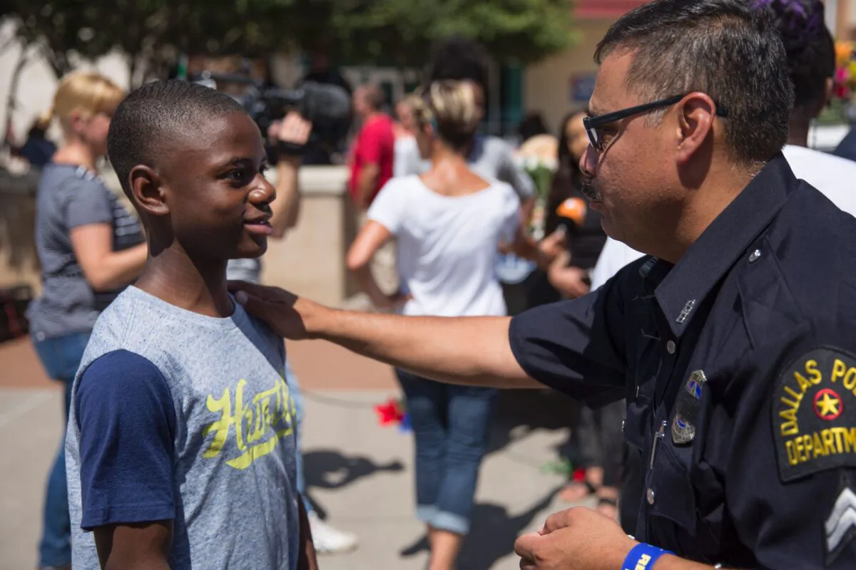 A police officer talks with a boy at a memorial at Dallas Police Headquarters on July 8, 2016. (Laura Buckman/AFP via Getty Images)