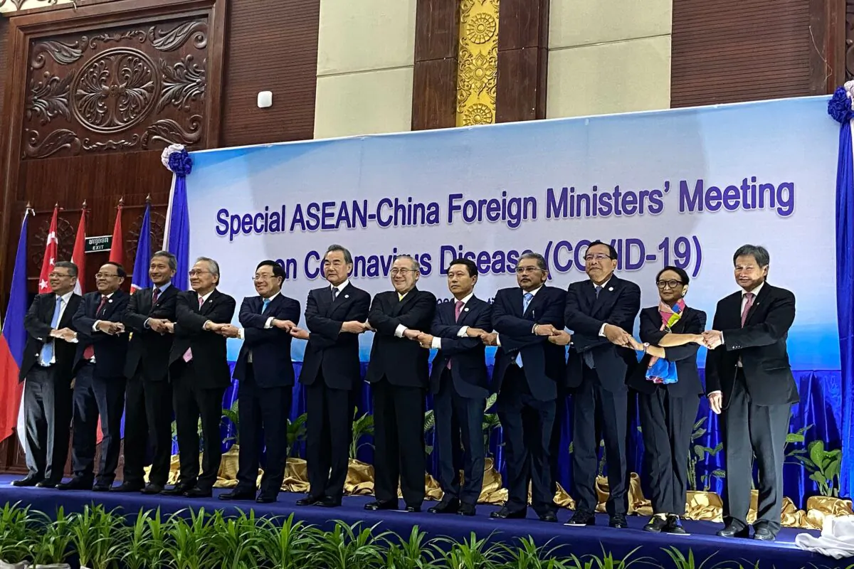 ASEAN Secretary-General Lim Jock Hoi and foreign ministers shake hands on stage at a summit between China and ASEAN (Association of Southeast Asian Nations) on the COVID-19 coronavirus in Vientiane, Laos, on Feb. 20, 2020. (Dene-Hern Chen/AFP via Getty Images)