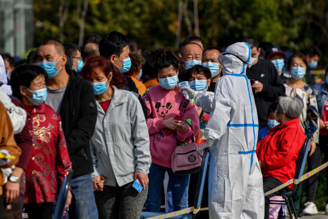 A health worker checks the temperature of residents as they line up to be tested for the COVID-19 in Qingdao, eastern China’s Shandong Province on Oct. 12, 2020. (STR/AFP via Getty Images)
