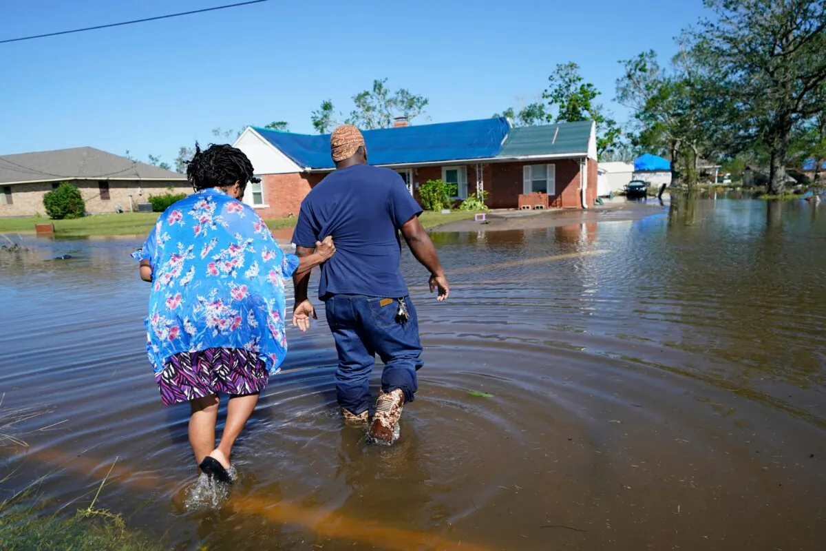 Soncia King holds onto her husband Patrick King as they walk through the flooded street to their home, after Hurricane Delta moved through on Friday, in Lake Charles, La., on Oct. 10, 2020. (Gerald Herbert/AP Photo)