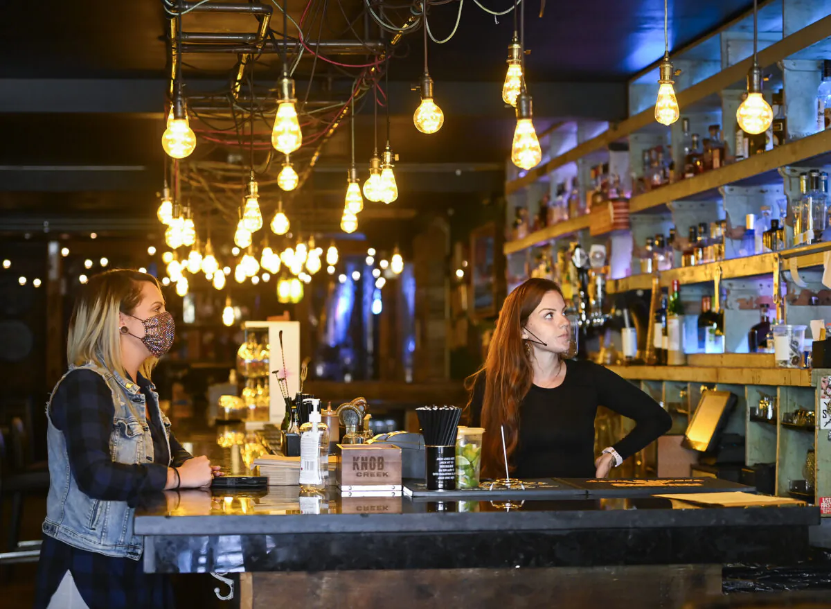 Staff members at a bar and restaurant watch the news on federal government announcements on a television in Mississauga, Ont., on Oct. 9, 2020. (The Canadian Press/Nathan Denette)