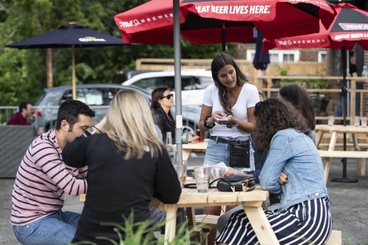 A server takes orders on the patio of a restaurant in Ottawa on June 12, 2020. (The Canadian Press/Justin Tang)