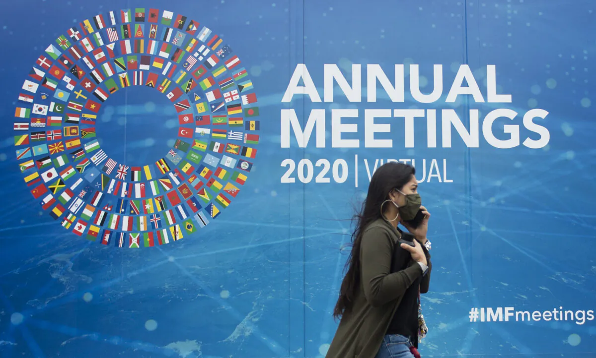 A woman walks past a promotional poster for the virtual 2020 Annual Meetings outside the International Monetary Fund at their headquarters in Washington, on October 13, 2020. (ANDREW CABALLERO-REYNOLDS/AFP via Getty Images)