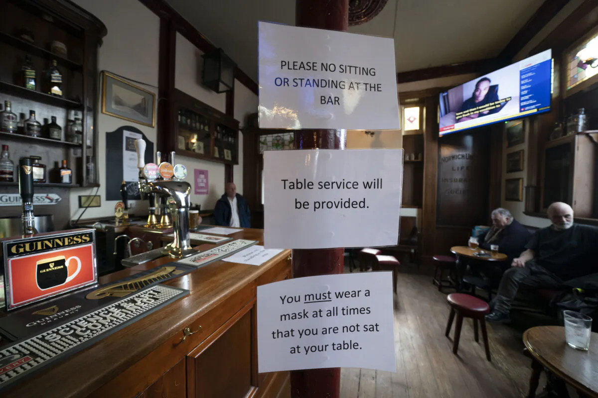 The British government has carved England into three tiers of risk in a bid to slow the spread of a resurgent CCP virus. People sit in the Dispensary pub in Liverpool, England, on Oct. 12, 2020. (Jon Super/AP Photo)