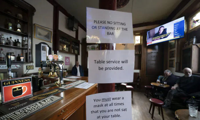 The British government has carved England into three tiers of risk in a bid to slow the spread of a resurgent CCP virus. People sit in the Dispensary pub in Liverpool, England, on Oct. 12, 2020. (Jon Super/AP Photo)
