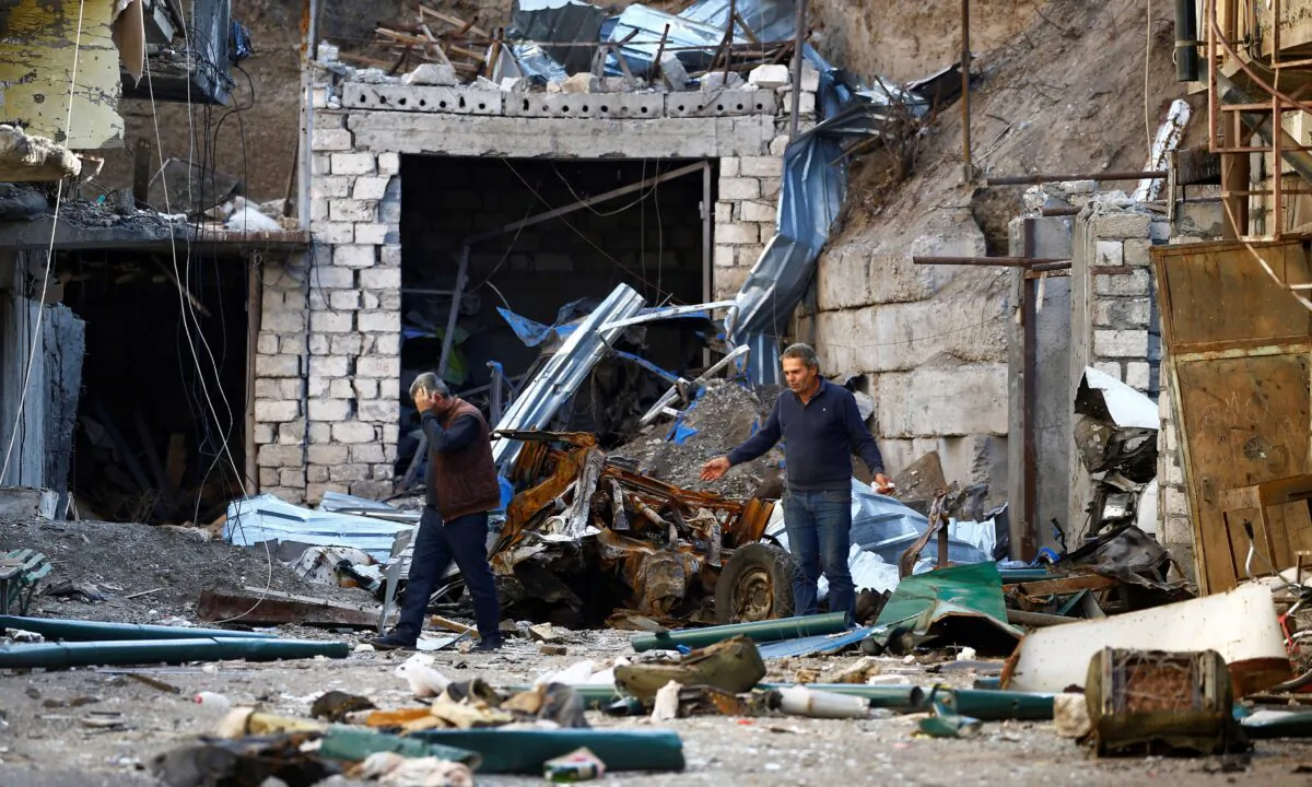 Men are seen among the ruins after recent shelling during the military conflict over the breakaway region of Nagorno-Karabakh, in Stepanakert, on Oct. 13, 2020. (Stringer/Reuters)