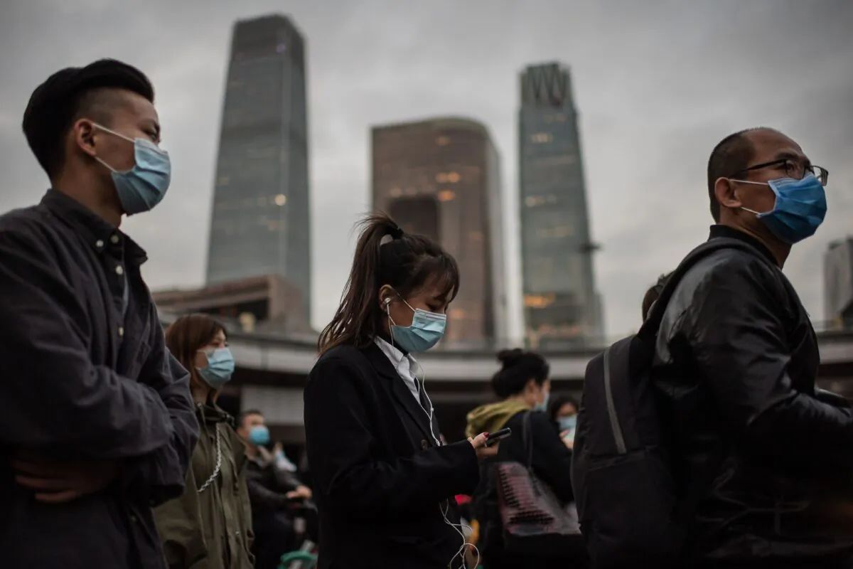 People wearing face masks as a preventive measure against COVID-19 wait at a red light to cross a street during rush hour in Beijing on Oct. 14, 2020. (Nicolas Asfouri/AFP via Getty Images)