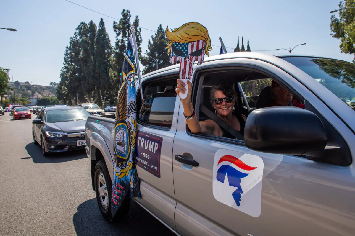 A woman holds pro-Trump signs during a Pro-Trump car caravan in Long Beach, Calif., on Oct. 3, 2020. (Apu Gomes AFP via Getty Images)