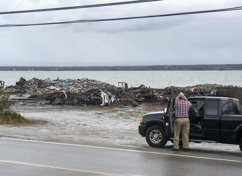 Debris from a burnt out fish plant is scattered along the shore in Middle West Pubnico, N.S., on Oct. 17, 2020. (Andrew Vaughan/The Canadian Press)