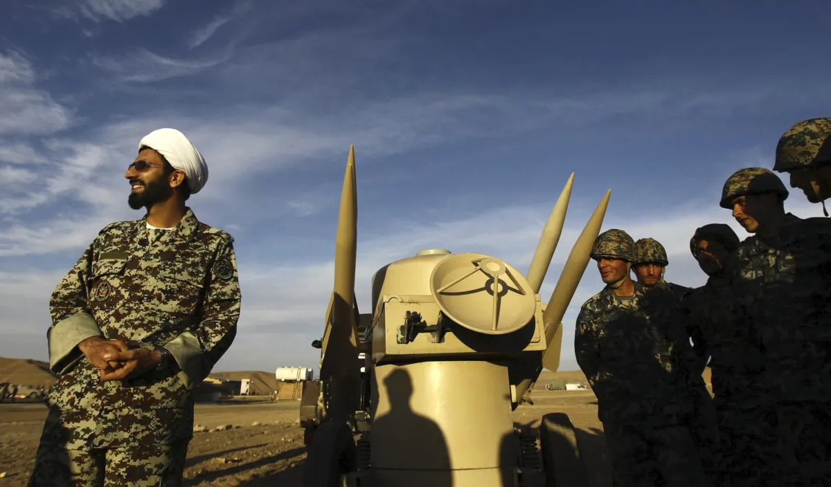 An Iranian clergyman stands next to missiles and army troops, during a manoeuvre, in an undisclosed location in Iran on Nov. 13, 2012. (Majid Asgaripour/Mehr News Agency via AP)