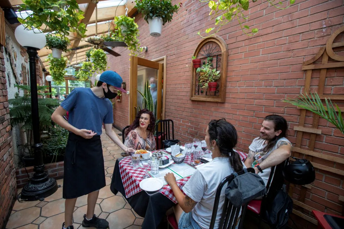A server at Mamma Martino's Restaurant serves customers after indoor dining restaurants, gyms, and cinemas re-open under Phase 3 rules from COVID-19 restrictions in Toronto, on July 31, 2020. (Reuters/Carlos Osorio)