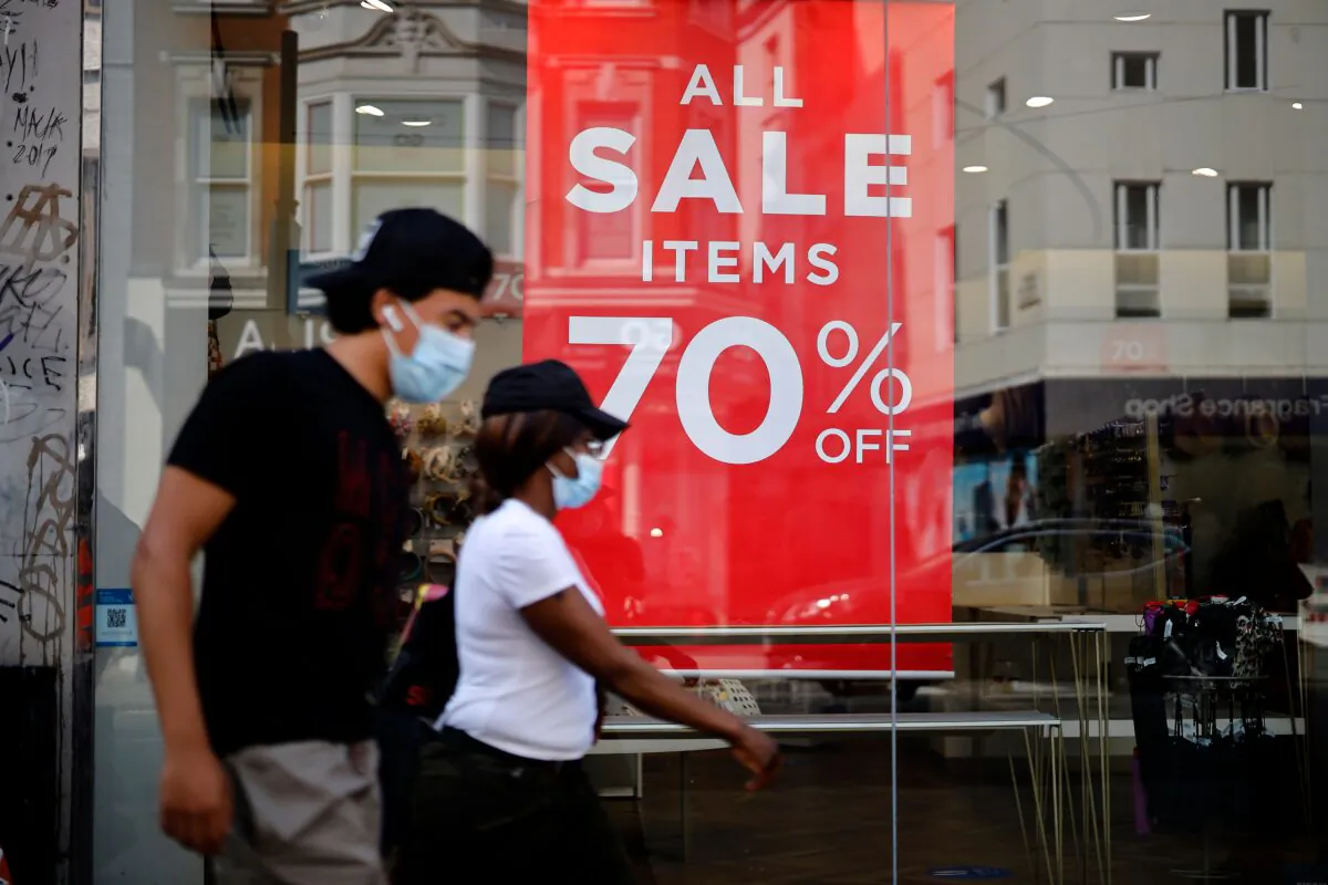 Shoppers wearing face masks walk past sales signs in the window of a shop in London on Aug. 12, 2020. (Tolga Akmen/AFP via Getty Images)
