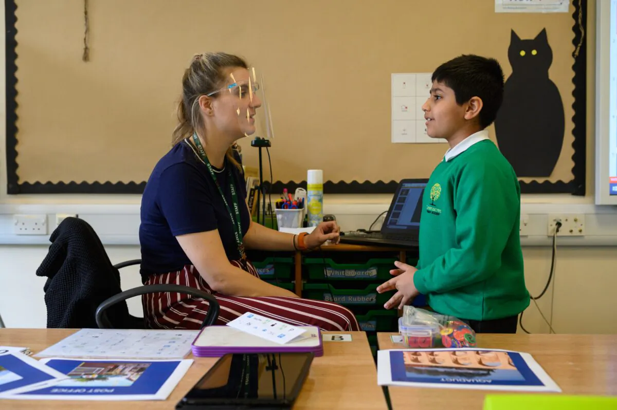 Class teacher Ruth Titmuss wears a PPE face shield as she speaks to a pupil at Greenacres Primary Academy in Oldham, northern England, on Sept. 2, 2020. (Oli Scarff/Getty Images)