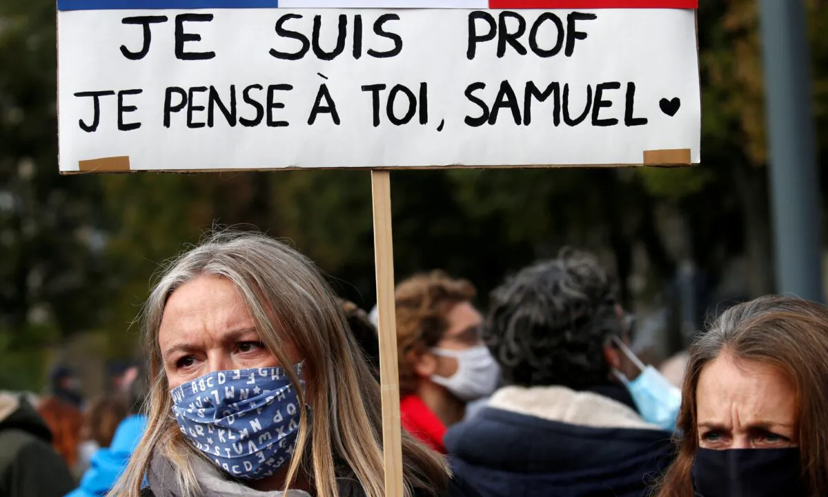 A woman holds a banner as she attends a tribute to Samuel Paty, the French teacher who was beheaded on the streets of the Paris suburb of Conflans St Honorine, at the Place de la Republique, in Lille, France, on Oct.18, 2020. (Pascal Rossignol/Reuters)