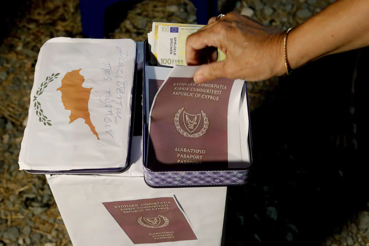 A demonstrator takes a mock copy of Cyprus passport during a demonstration against corruption outside of the conference center in the capital Nicosia, Cyprus, on Oct. 14, 2020. (Petros Karadjias/AP Photo)
