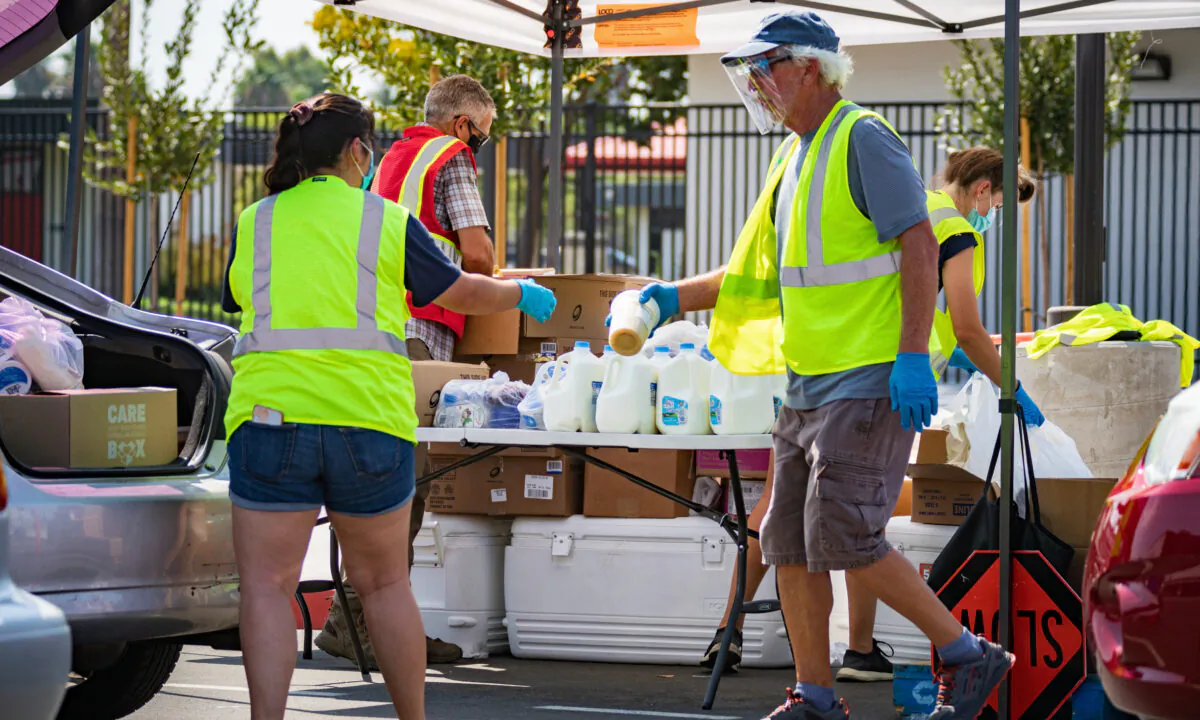 Volunteers distribute food to the needy at a drive-thru food pantry run by Saddleback Church in Anaheim, Calif., on Aug. 18, 2020. (John Fredricks/The Epoch Times)
