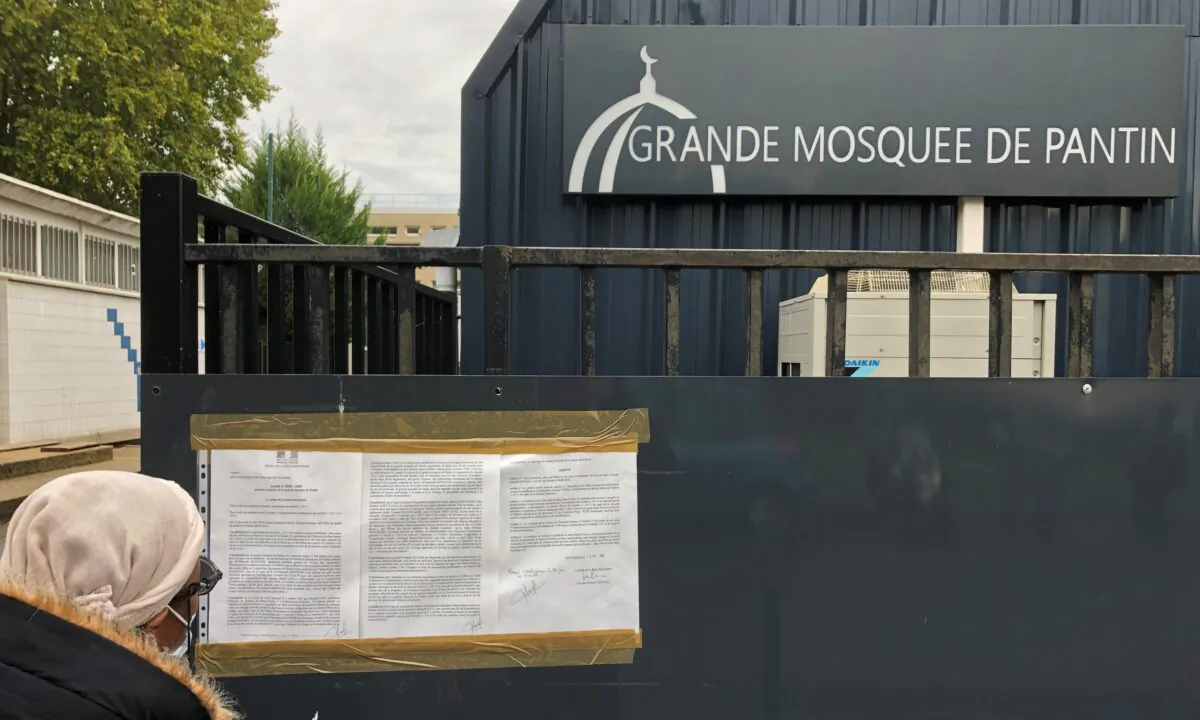 A woman reads a prefectoral decree installed on the entrance gates of the Grand Mosque of Pantin, near Paris, France, On Oct. 20, 2020. (Antony Paone/Reuters)