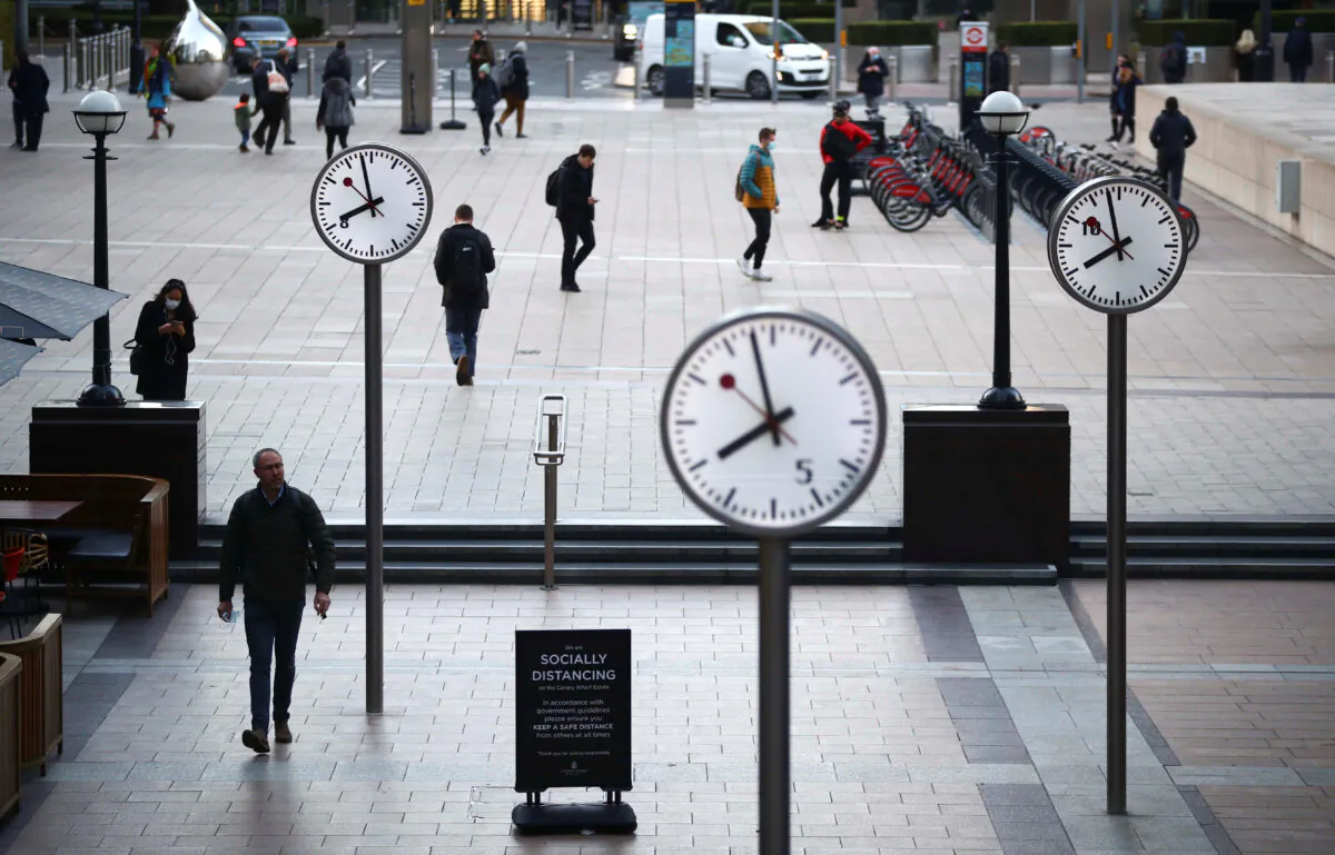 People walk during the morning rush hour in Canary Wharf amid the outbreak of the CCP virus in London on Oct. 15, 2020. (Reuters/Hannah McKay)
