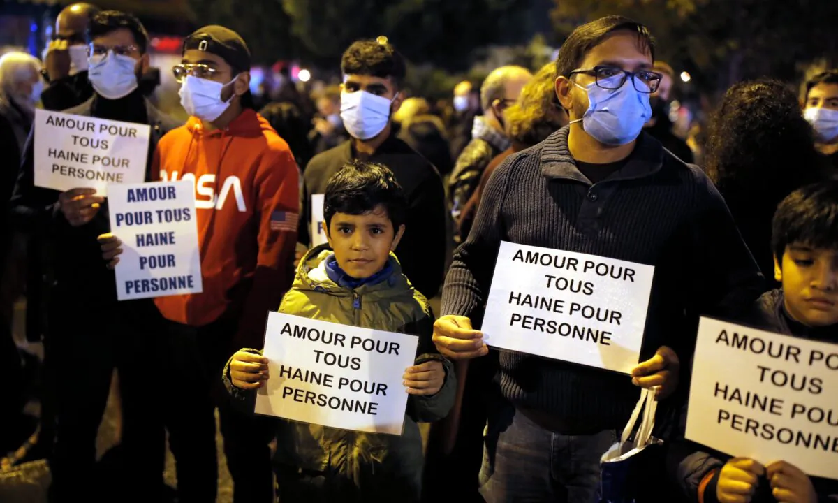 People hold posters reading "Love for all, hate for no one" during a memorial march in homage to the history teacher who was beheaded last week, in Conflans-Sainte-Honorine, northwest of Paris, on Oct. 20, 2020. (Lewis Joly/AP Photo)