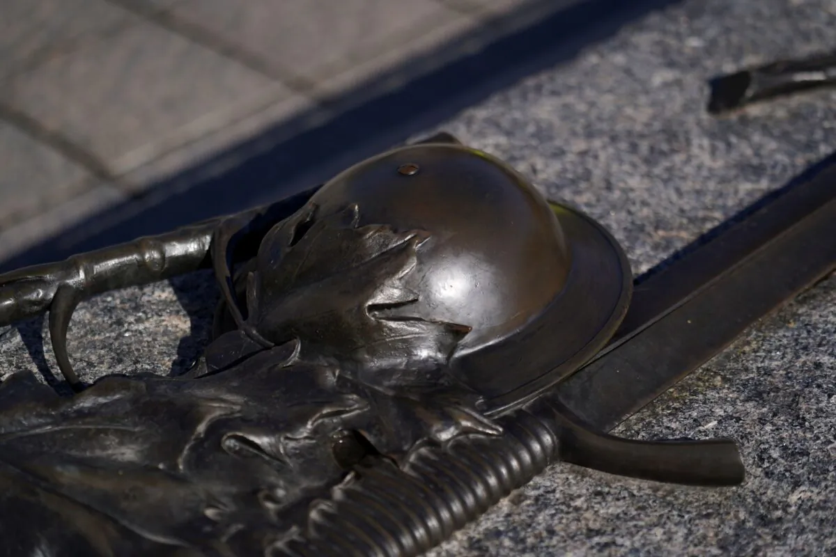 A bronzesmith restored the helmet on the Tomb of the Unknown Soldier at the National War Memorial in Ottawa Oct. 17, 2020, after it was vandalized on Oct. 16. (The Canadian Press/Justin Tang)