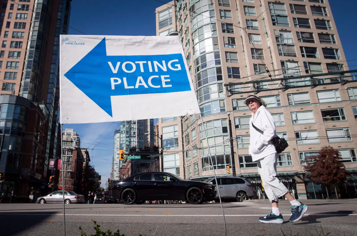 A woman walks past a sign directing people to a polling station in Vancouver Oct. 20, 2018. British Columbians are heading to the polls to cast their votes in municipal elections being held across the province. THE CANADIAN PRESS/Darryl Dyck