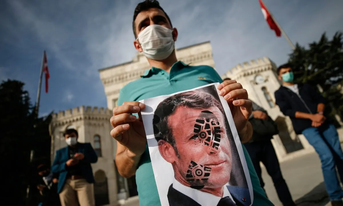 A youth holds a photograph of France's President Emmanuel Macron, stamped with a shoe mark, during a protest against France in Istanbul, Turkey, on Oct. 25, 2020. (Emrah Gurel/AP Photo)