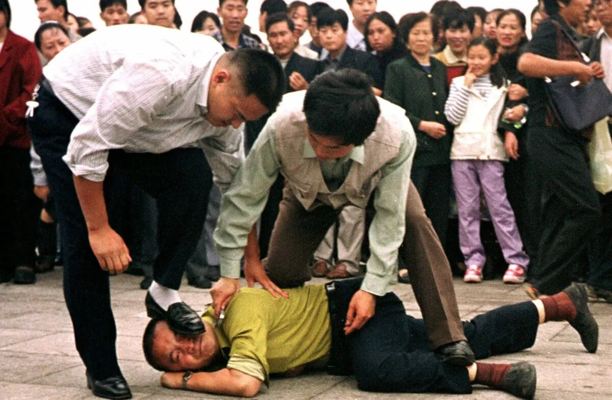Police detain a Falun Gong protester in Tiananmen Square as a crowd watches in Beijing on Oct. 1, 2000. (Chien-min Chung/AP Photo)