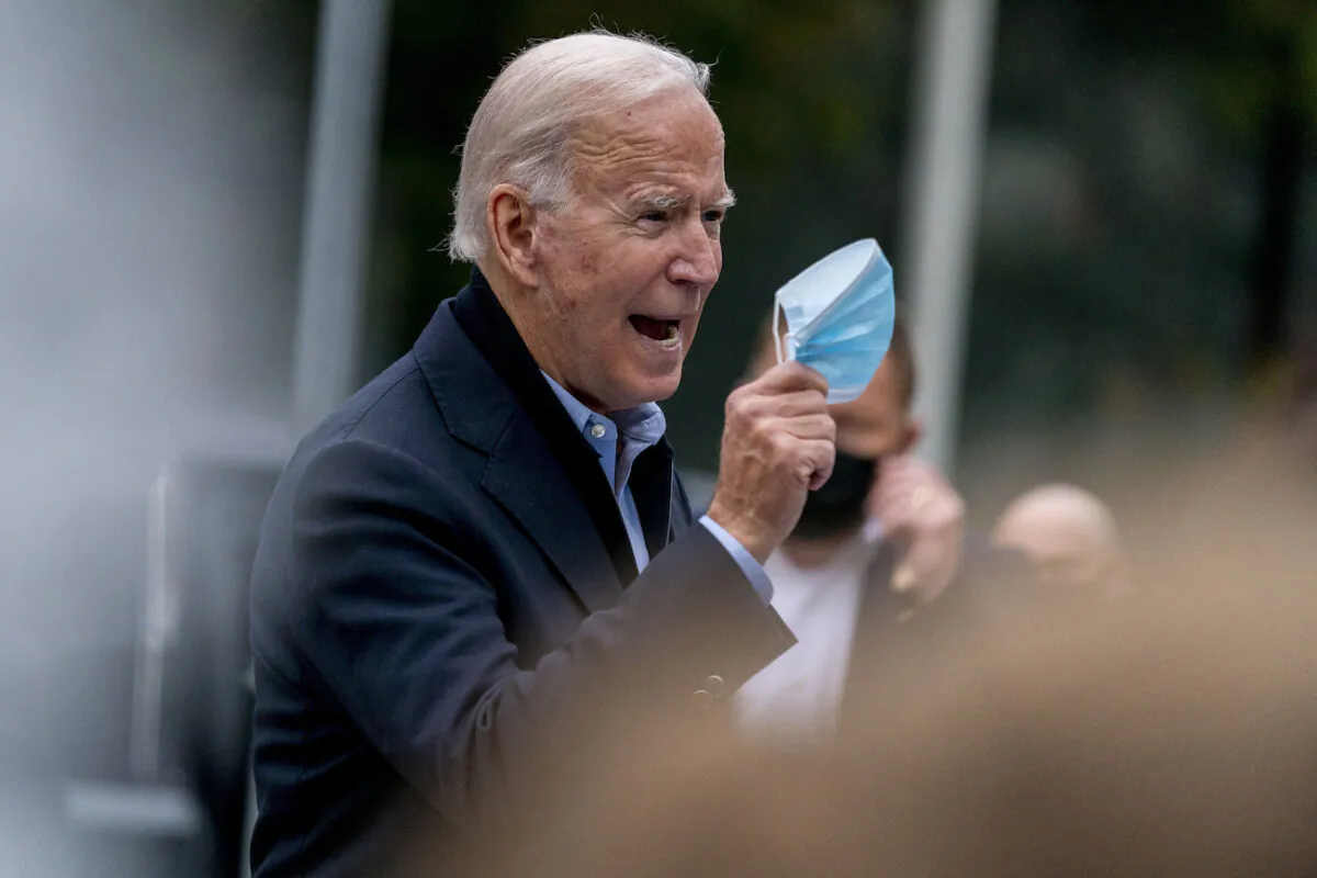 Democratic presidential candidate Joe Biden holds up his face mask as he speaks to members of the media outside a voter service center, in Chester, Pa., Oct. 26, 2020. (AP Photo/Andrew Harnik)