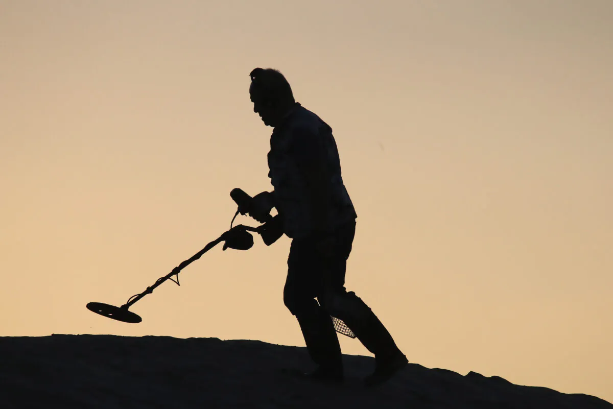 A man uses a metal detector on Venice Beach, California, in the morning of Dec. 15, 2019. (Bruce Bennett/Getty Images)