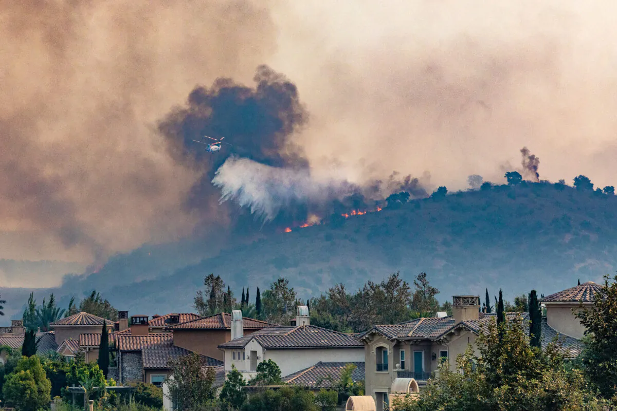 A firefighting helicopter drops water on the Blue Ridge Fire seen from Yorba Linda, Calif., on Oct. 27, 2020. (John Fredricks/The Epoch Times)