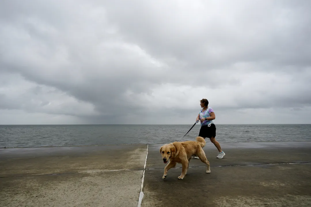 Jane McDow walks with her dog ‘Duke’ along the Lake Pontchartrain seawall in New Orleans, on Oct. 28, 2020. (Gerald Herbert/AP)