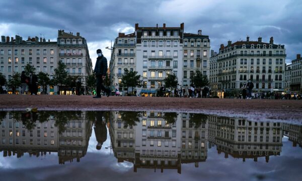 A man wearing a mask walks in the street in the center of Lyon