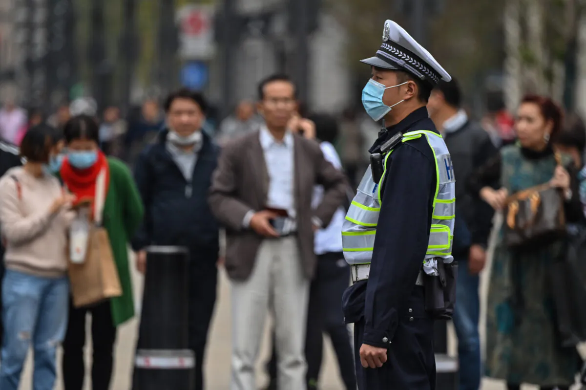 A police officer wearing a face mask monitors pedestrian traffic along a street in Shanghai on Oct. 28, 2020. (Hector Retamal/AFP via Getty Images)
