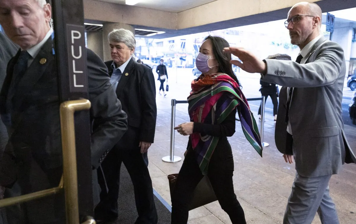Huawei CFO Meng Wanzhou is flanked by a security team as she arrives at B.C. Supreme Court in downtown Vancouver on Oct. 29, 2020. (Jonathan Hayward/The Canadian Press)