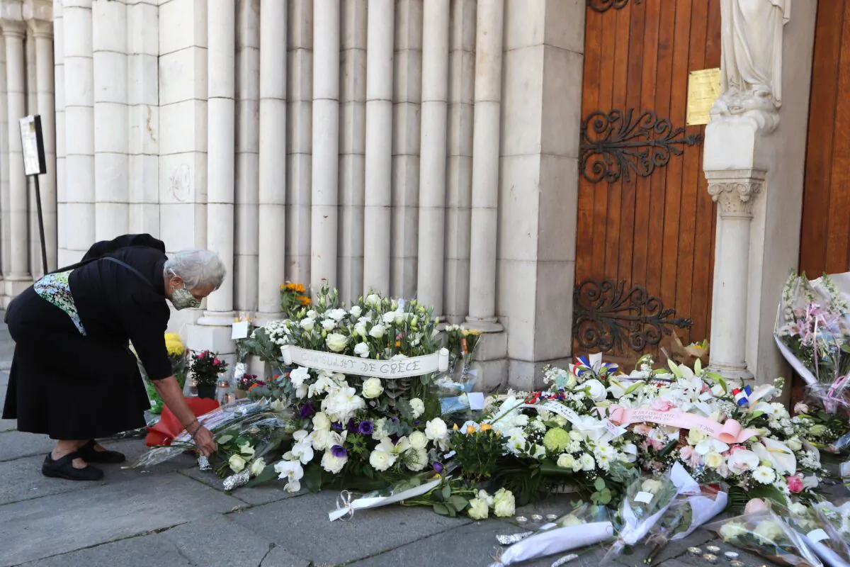 A woman, wearing a face mask, lays flowers in front of the Notre-Dame de l'Assomption Basilica in Nice on Oct. 30, 2020 during a tribute to the victims killed by a knife attacker the day before. (Valery Hache/AFP via Getty Images)