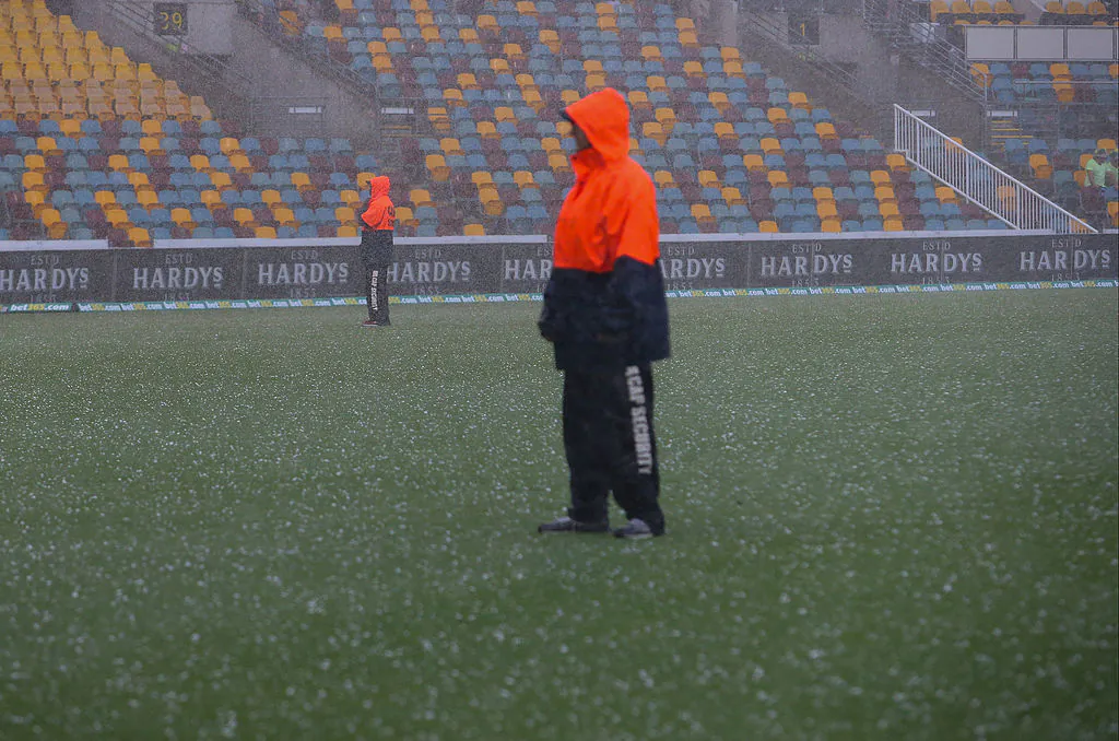 Security staff stand on the playing field following a hailstorm on day four of the first Ashes cricket Test match between England and Australia at the Gabba Cricket Ground in Brisbane on November 24, 2013.(PATRICK HAMILTON/AFP via Getty Images)