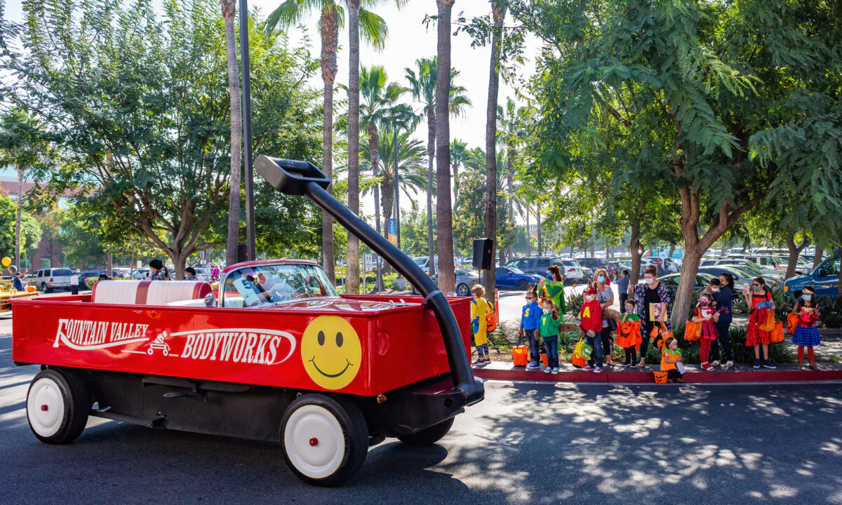 A car decorated as a giant red wagon passes by costumed children at the 14th annual Fountain Valley Hospital Trick-or-Treat Parade in Fountain Valley, Calif., on Oct. 30, 2020. (John Fredricks/The Epoch Times)