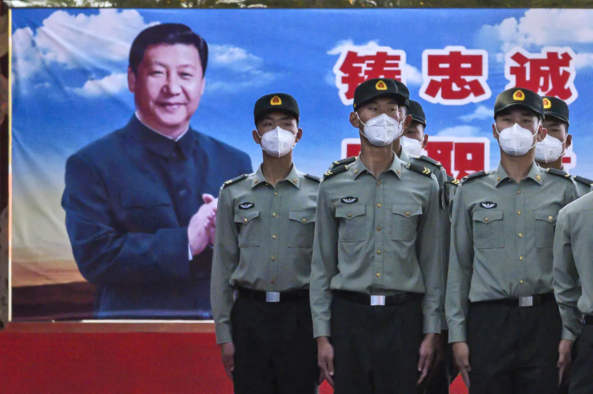 Soldiers of the People's Liberation Army's Honor Guard Battalion wear protective masks as they stand at attention in front of a photo of Chinese Communist Party leader Xi Jinping at their barracks outside the Forbidden City, near Tiananmen Square, in Beijing, on May 20, 2020. (Kevin Frayer/Getty Images)