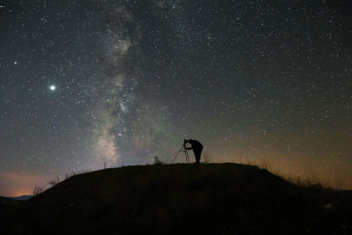 A person takes a photo with a camera on a tripod of the Milky Way (ADEM ALTAN/AFP via Getty Images)
