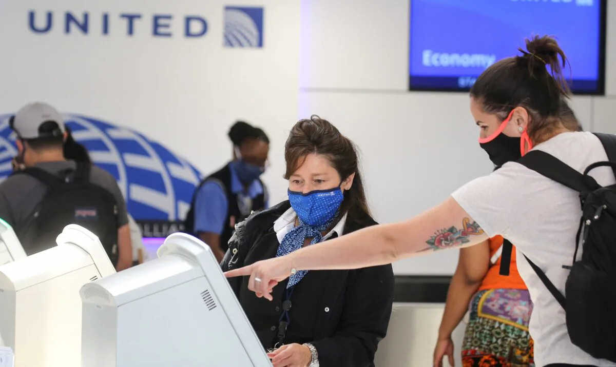 A United Airlines employee wears a required face covering along with a passenger at check-in at Los Angeles International Airport (LAX) amid the COVID-19 pandemic, in Los Angeles, on Oct. 1, 2020. (Mario Tama/Getty Images)