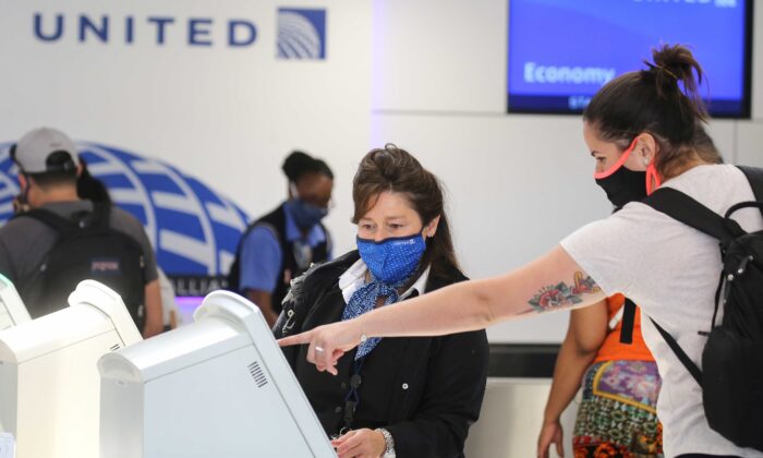 A United Airlines employee wears a required face covering along with a passenger at check-in at Los Angeles International Airport (LAX) amid the COVID-19 pandemic, in Los Angeles, Calif., on Oct. 1, 2020. (Mario Tama/Getty Images)