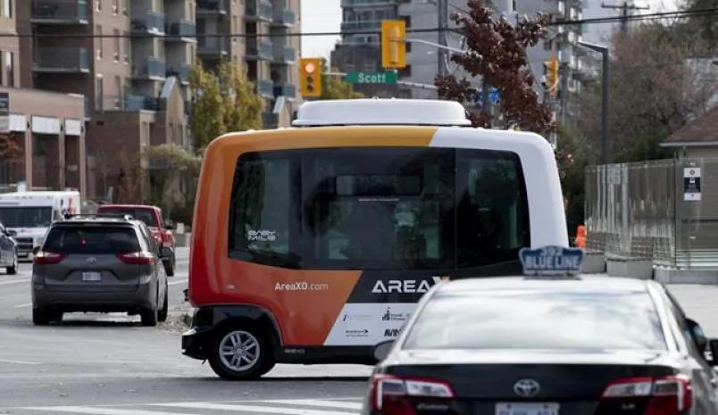 A low-speed autonomous shuttle rides past a taxi during a demonstration on roads around government buildings in Ottawa, on Nov. 2, 2020. (The Canadian Press/Adrian Wyld)