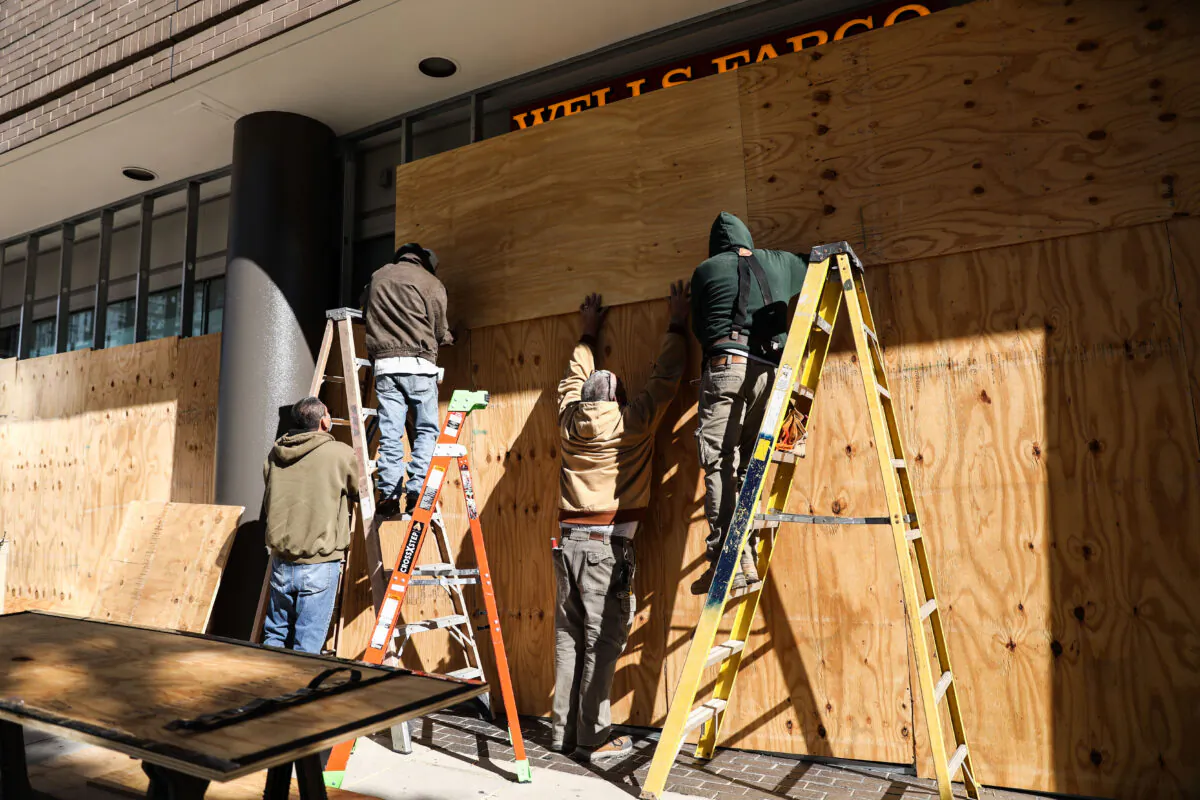 Workers board up store windows in preparation for Election Day, in downtown Washington near the White House, on Nov. 2, 2020. (Charlotte Cuthbertson/The Epoch Times)