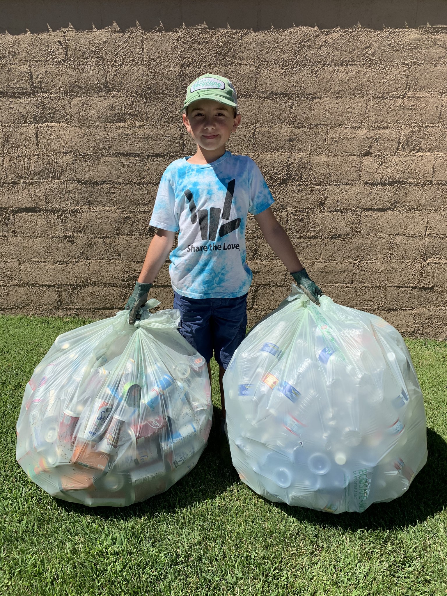 Young boy (6-8) holding an armful of recyclable plastic bottles